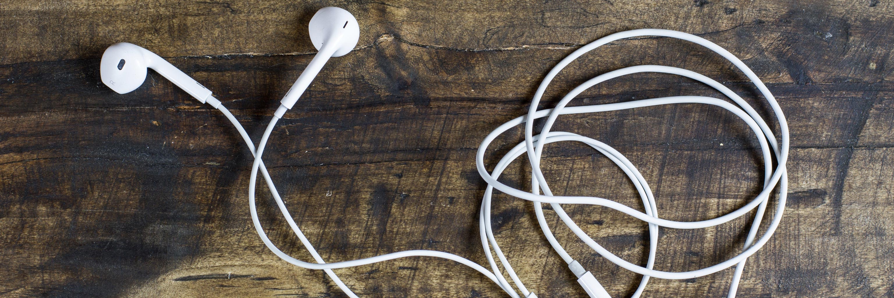 A pair of white earphones lying on a wooden surface
