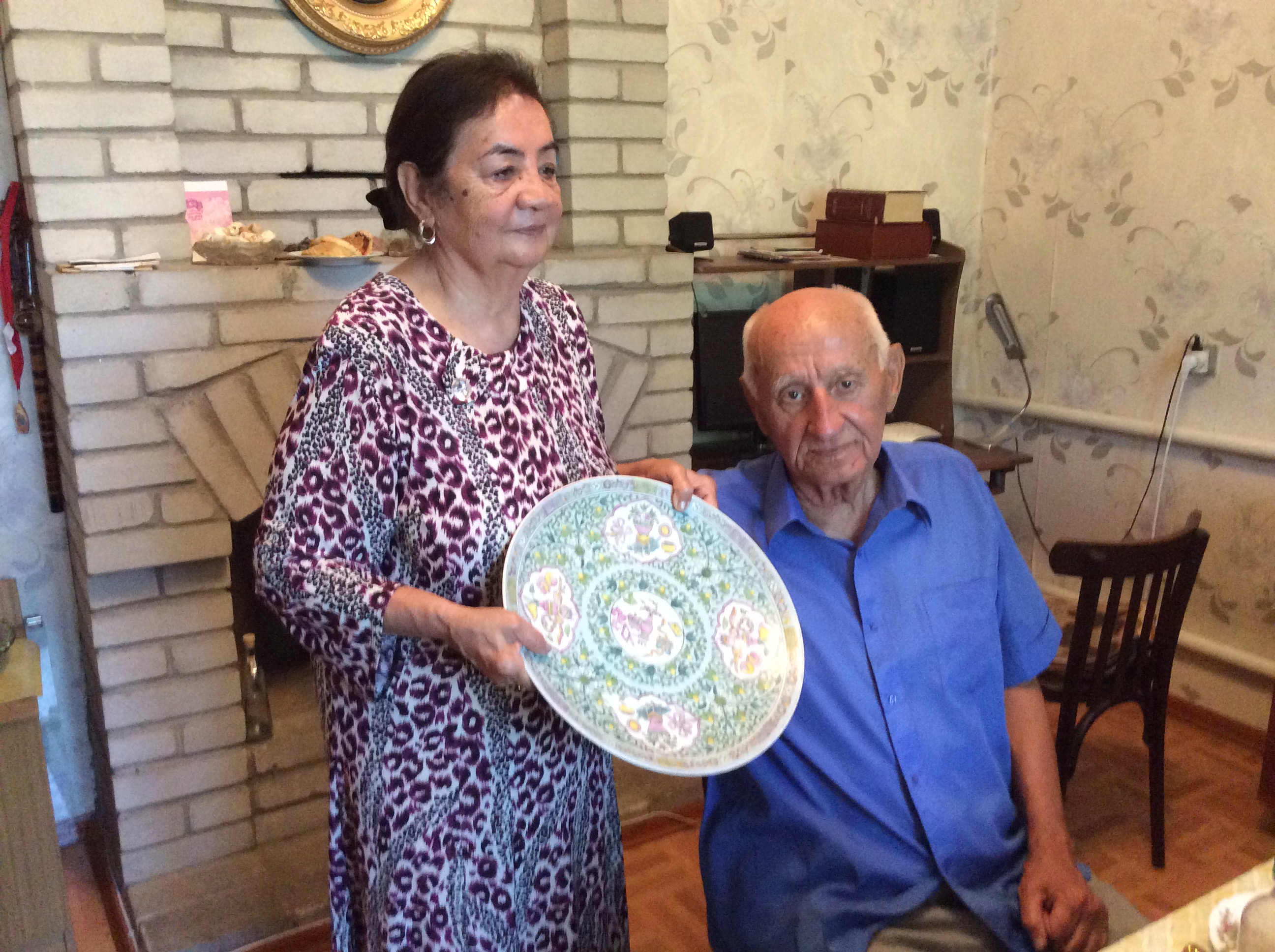 A Uyghur couple poses with a plate they received for their wedding.
