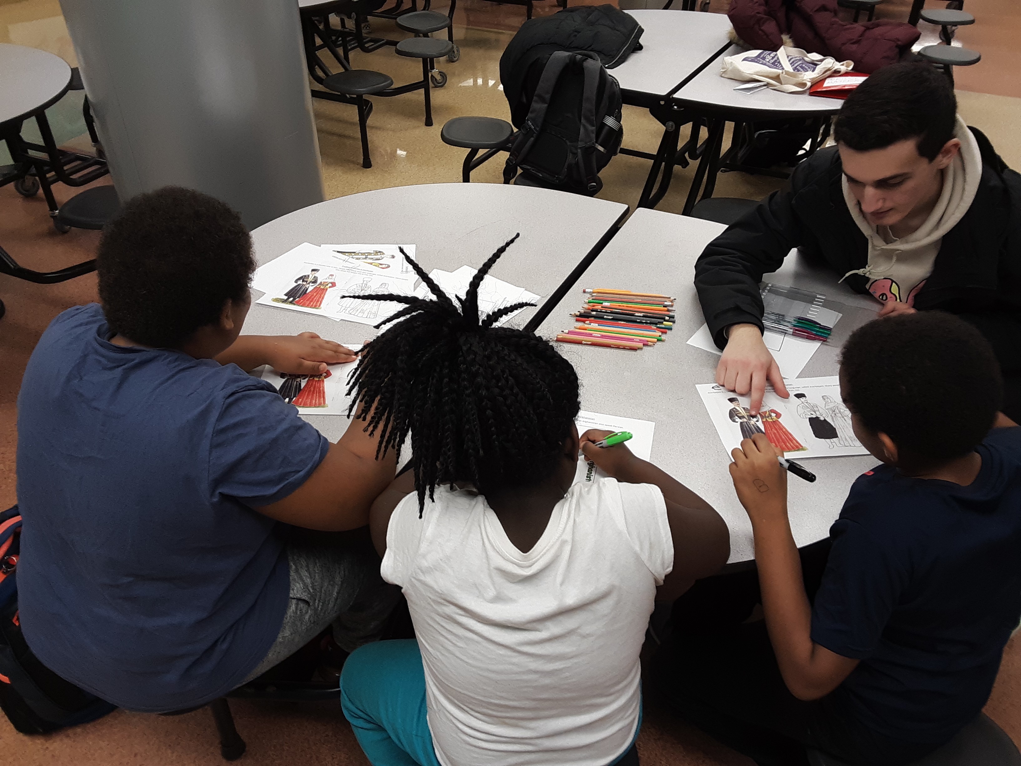 Man teaching kids at table about traditional clothes