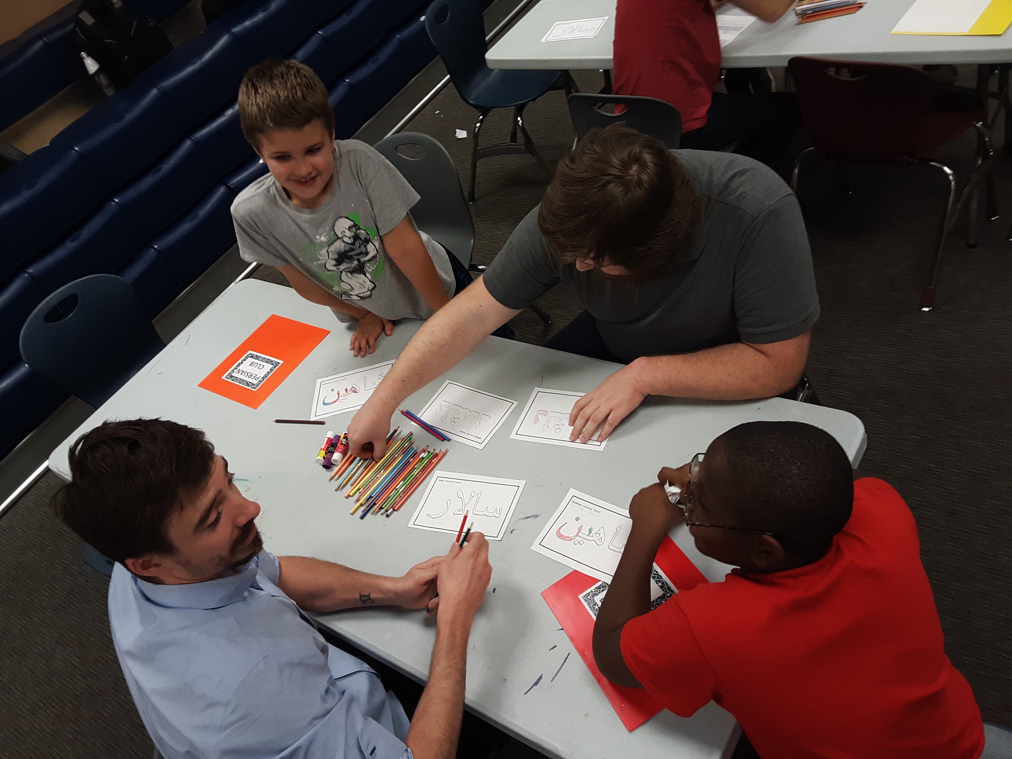 Two students teaching younger kids at table