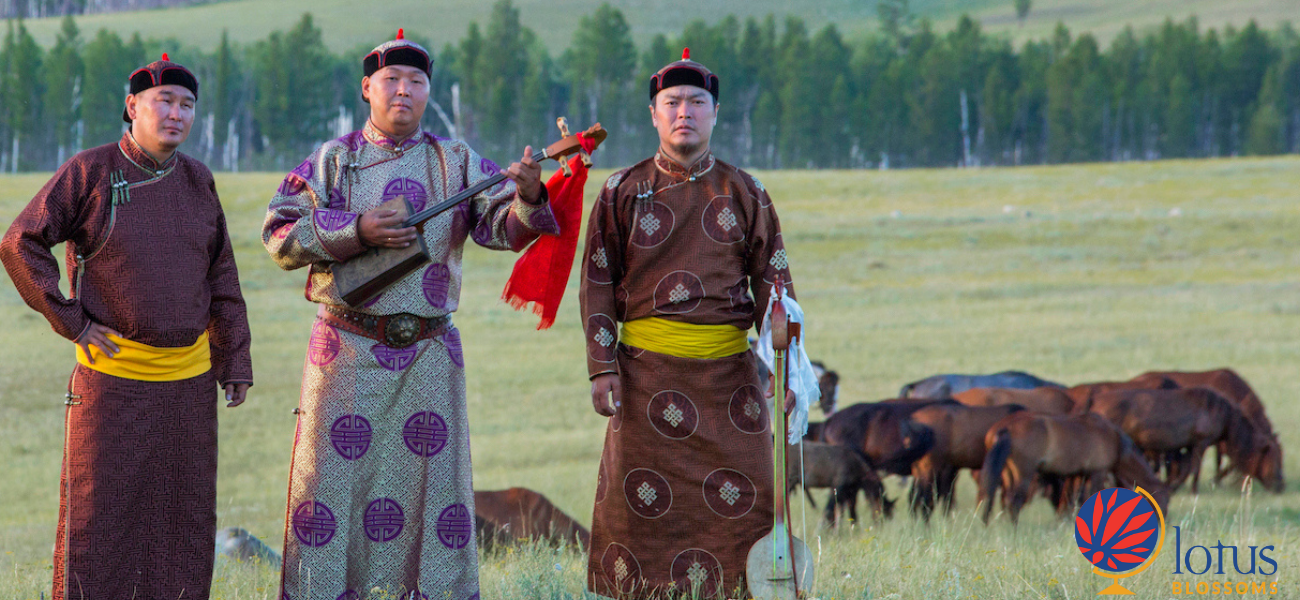 Three men holding instruments in a field in front of cows.