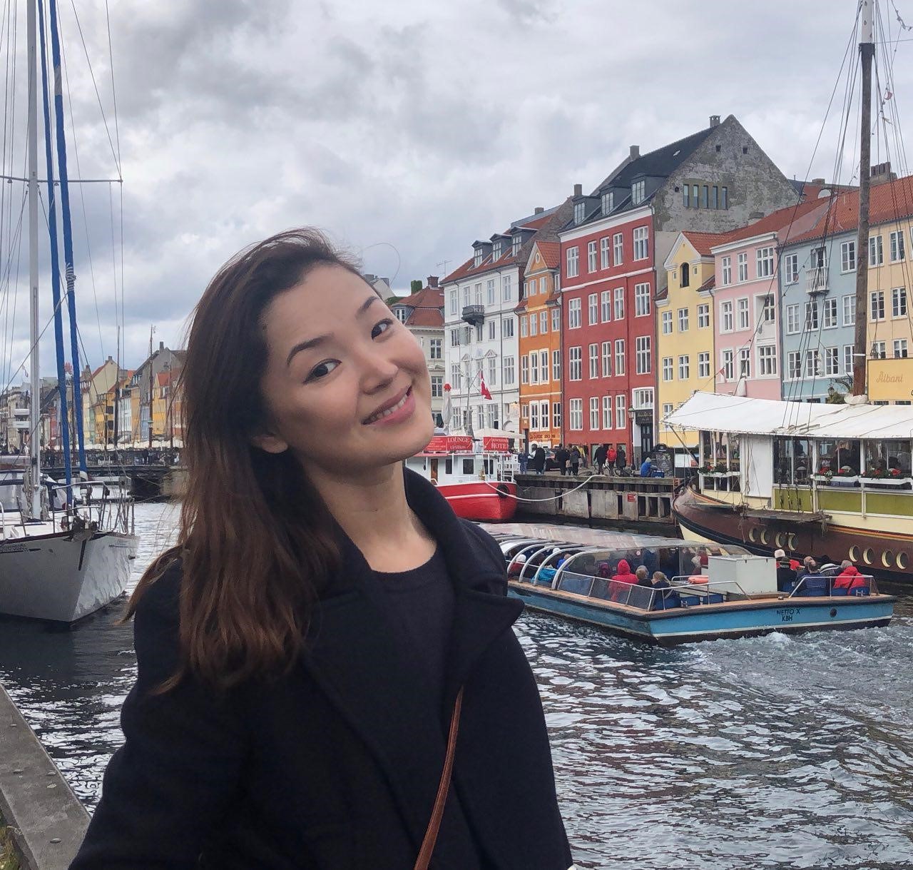 Student posed on a boardwalk in front of colorful buildings in Europe.