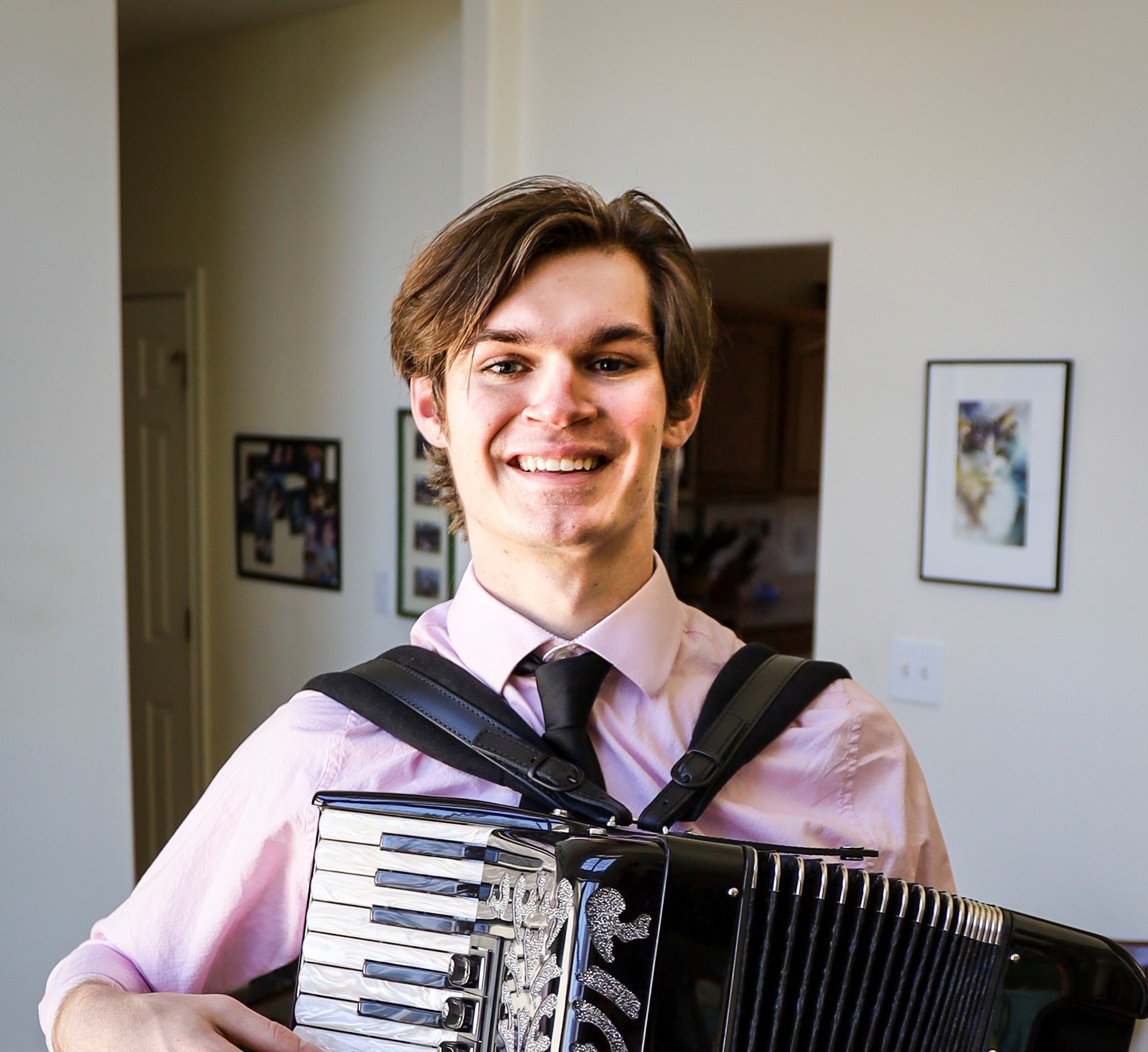Young man smiling, holding an accordion