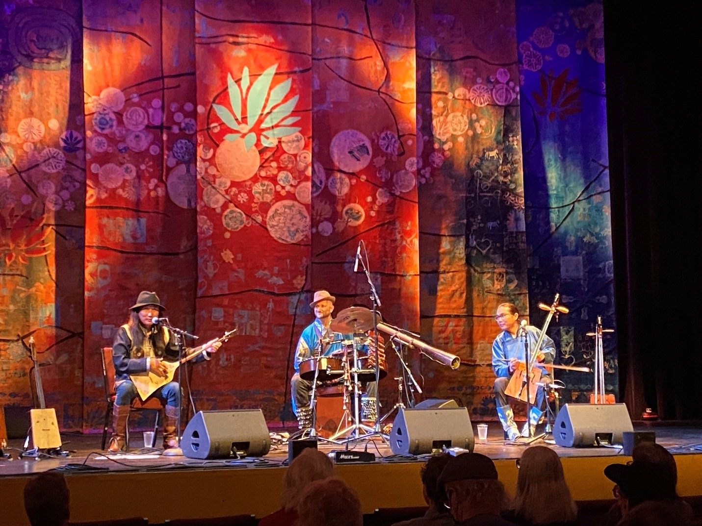 Three men playing various instruments at event on a stage